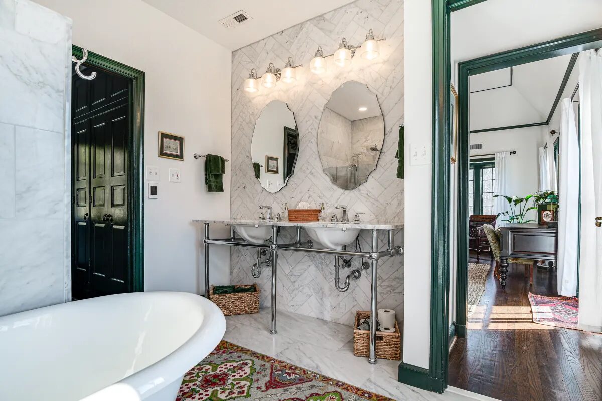 Master bath with double console sinks, herringbone marble backsplash, and green trim — Hunt Valley Tudor Gatehouse