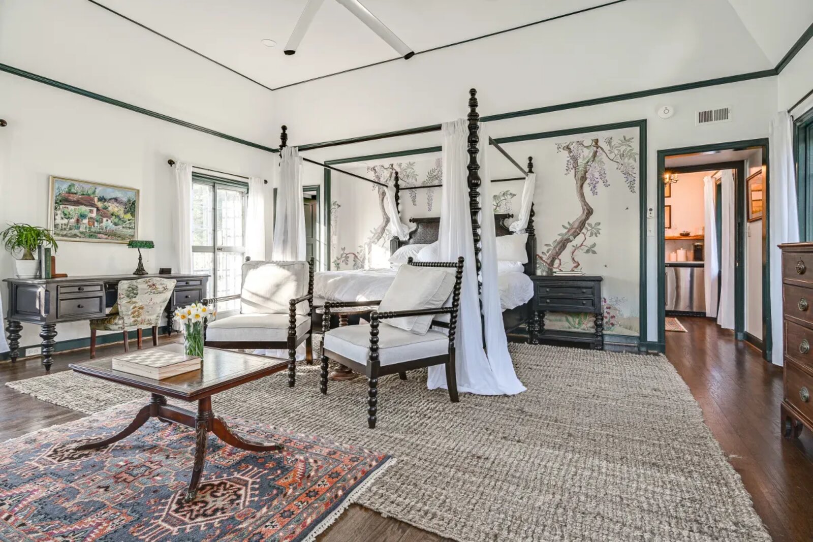 Master suite renovation — four-poster canopy bed with hand-painted wisteria mural, dark hardwood floors, and green painted trim